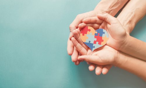 Adult,And,Chiild,Hands,Holding,Jigsaw,Puzzle,Heart,Shape,,Autism